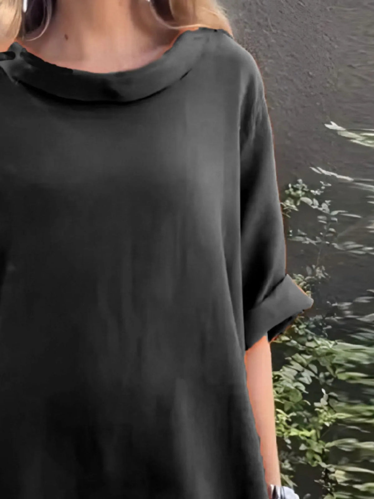 Person wearing a black oversized shirt with a blurred background
