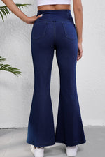Navy blue flared jeans worn by a person against a white background