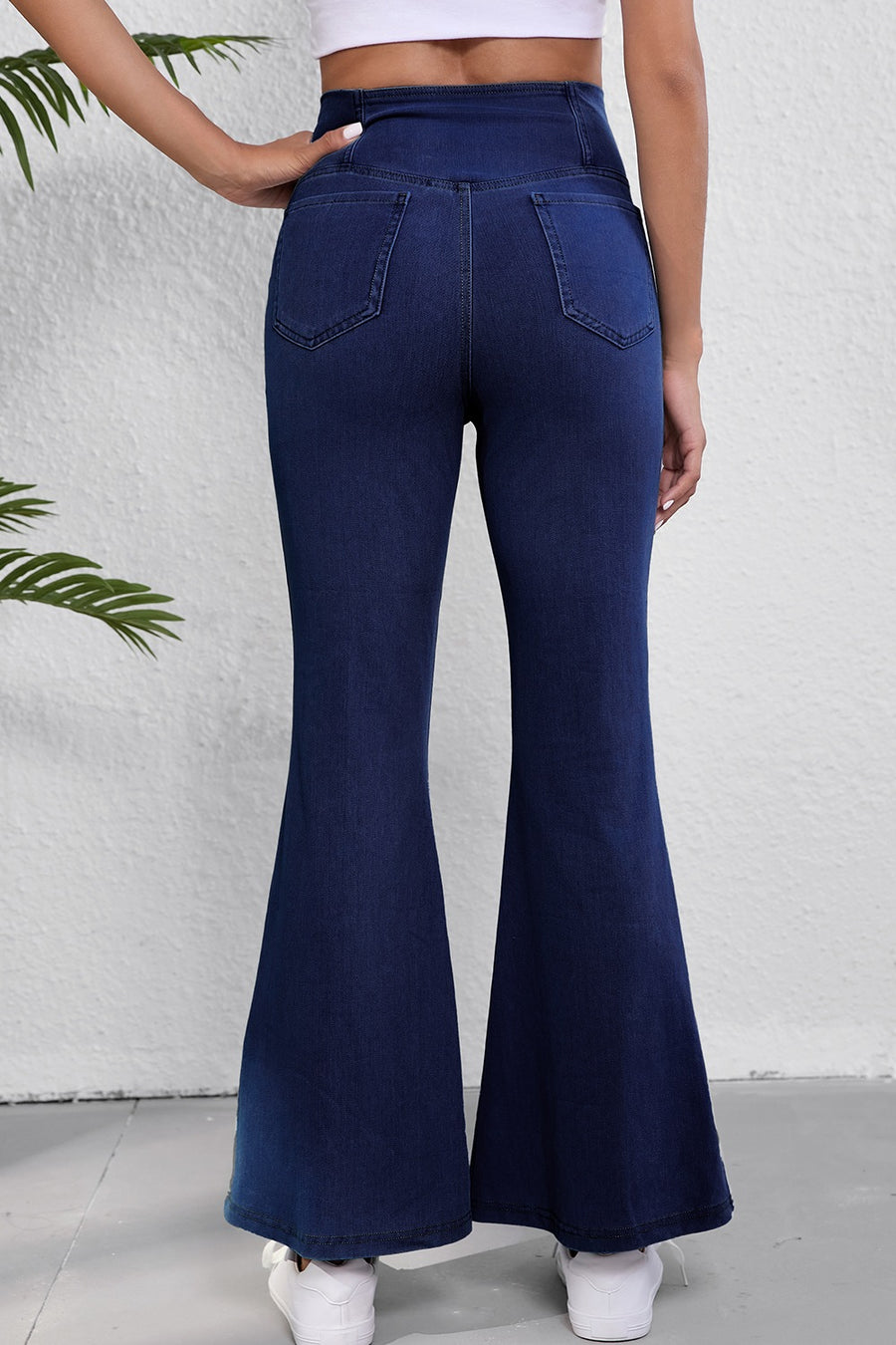 Navy blue flared jeans worn by a person against a white background
