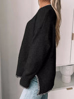 Person wearing a black sweater with white trim, standing against a neutral background.
