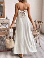 Woman in a white dress holding a straw bag in a room with wooden furniture.
