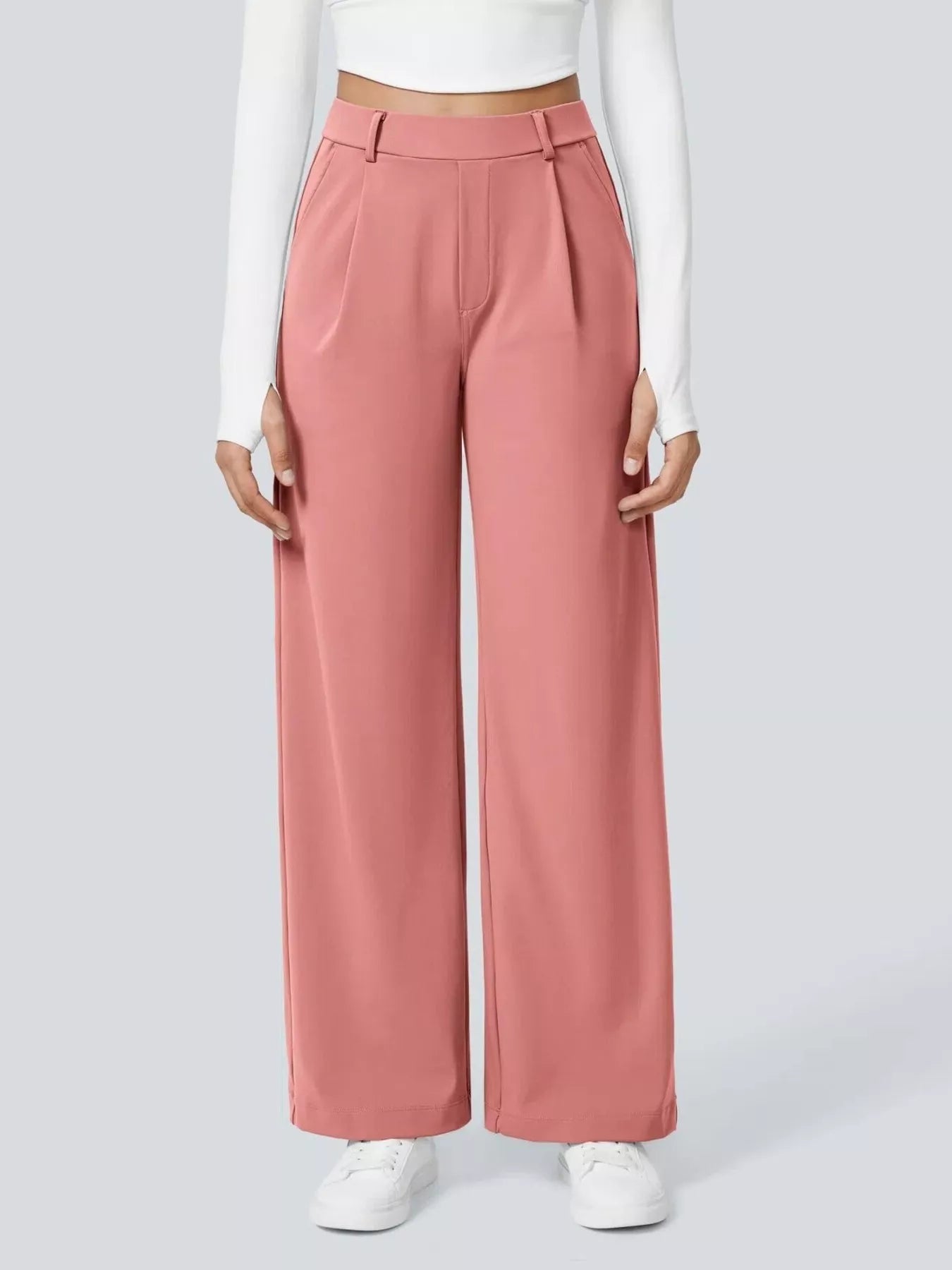 Person wearing pink wide-leg pants and white shoes on a light gray background