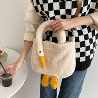 Person holding a fluffy goose-shaped handbag with a checkered sweater and jeans.