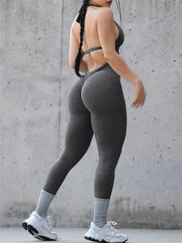 Person wearing gray leggings and white sneakers against a concrete wall.