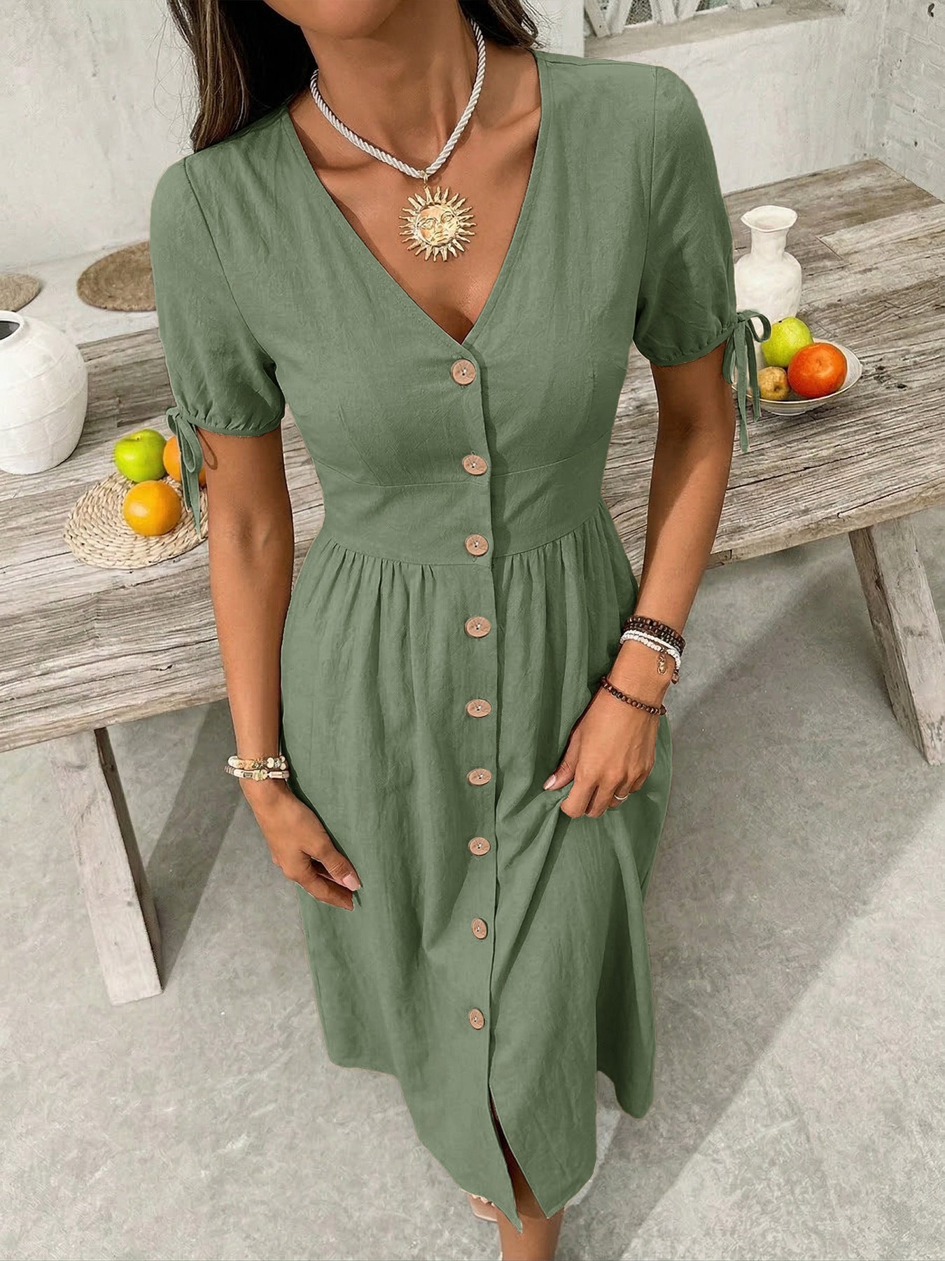 Woman wearing a green dress with a wooden table and fruits in the background