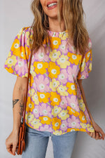 Woman wearing a colorful floral blouse against a plain background