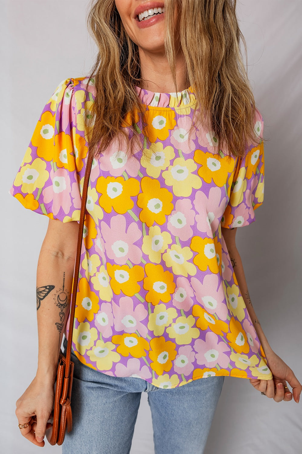 Woman wearing a colorful floral blouse against a plain background