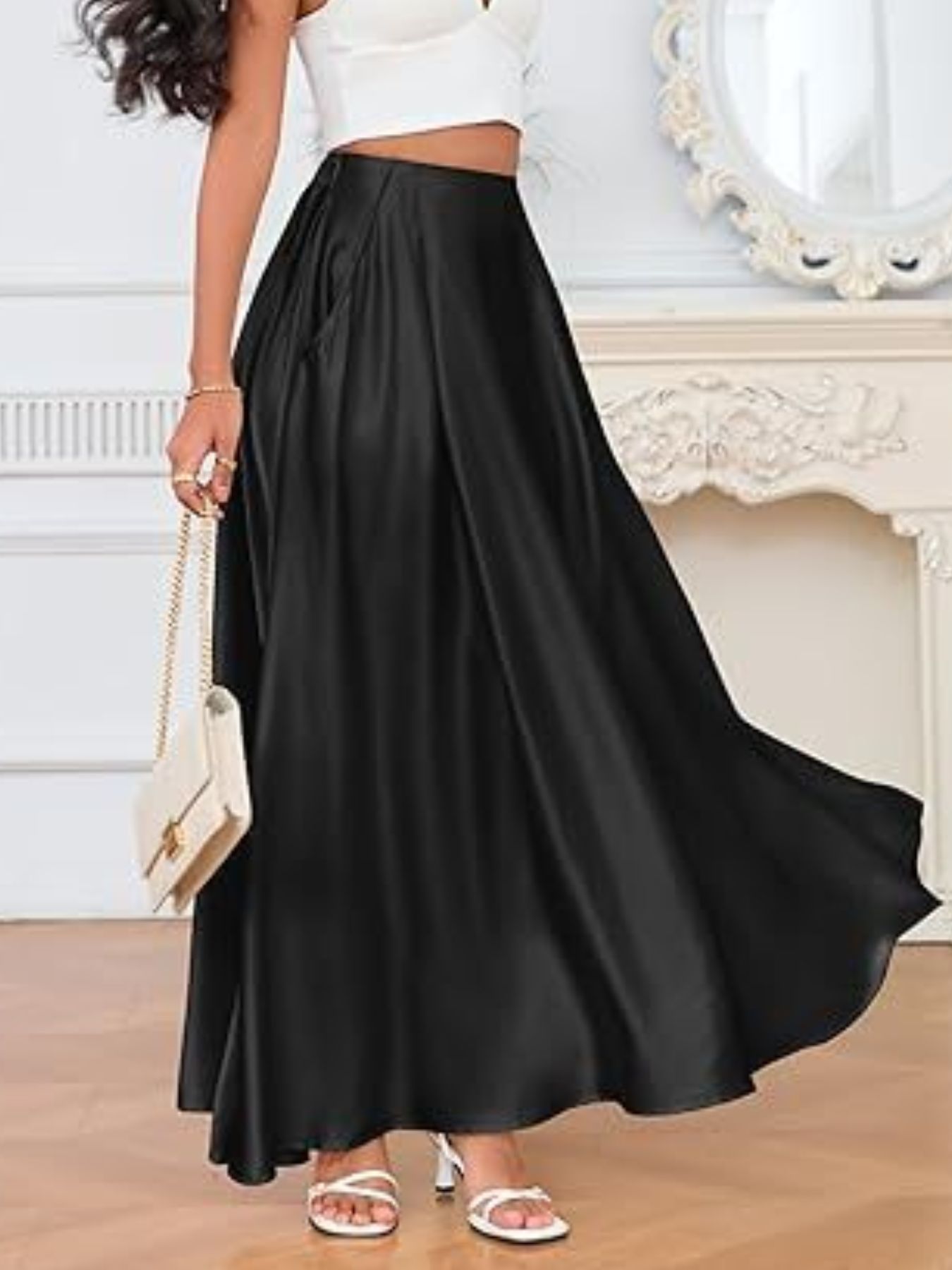 Person wearing a long black skirt with a white top in a room setting.