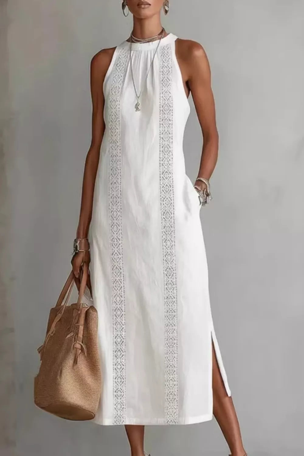 Woman wearing a white sleeveless dress with embroidery, holding a brown bag against a neutral background.