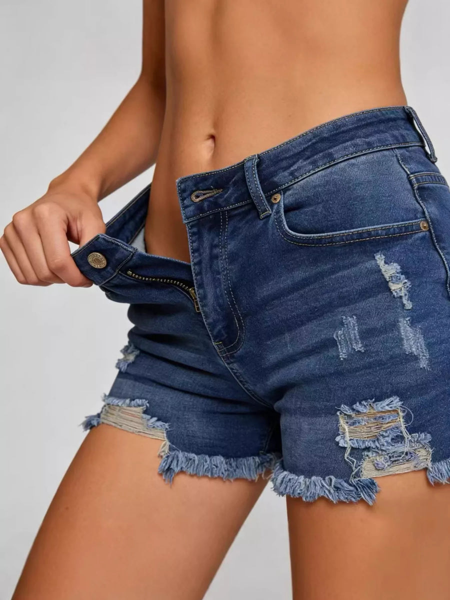 Person wearing blue denim shorts on a plain background