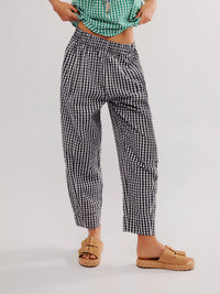 Person wearing black and white checkered pants on a plain background