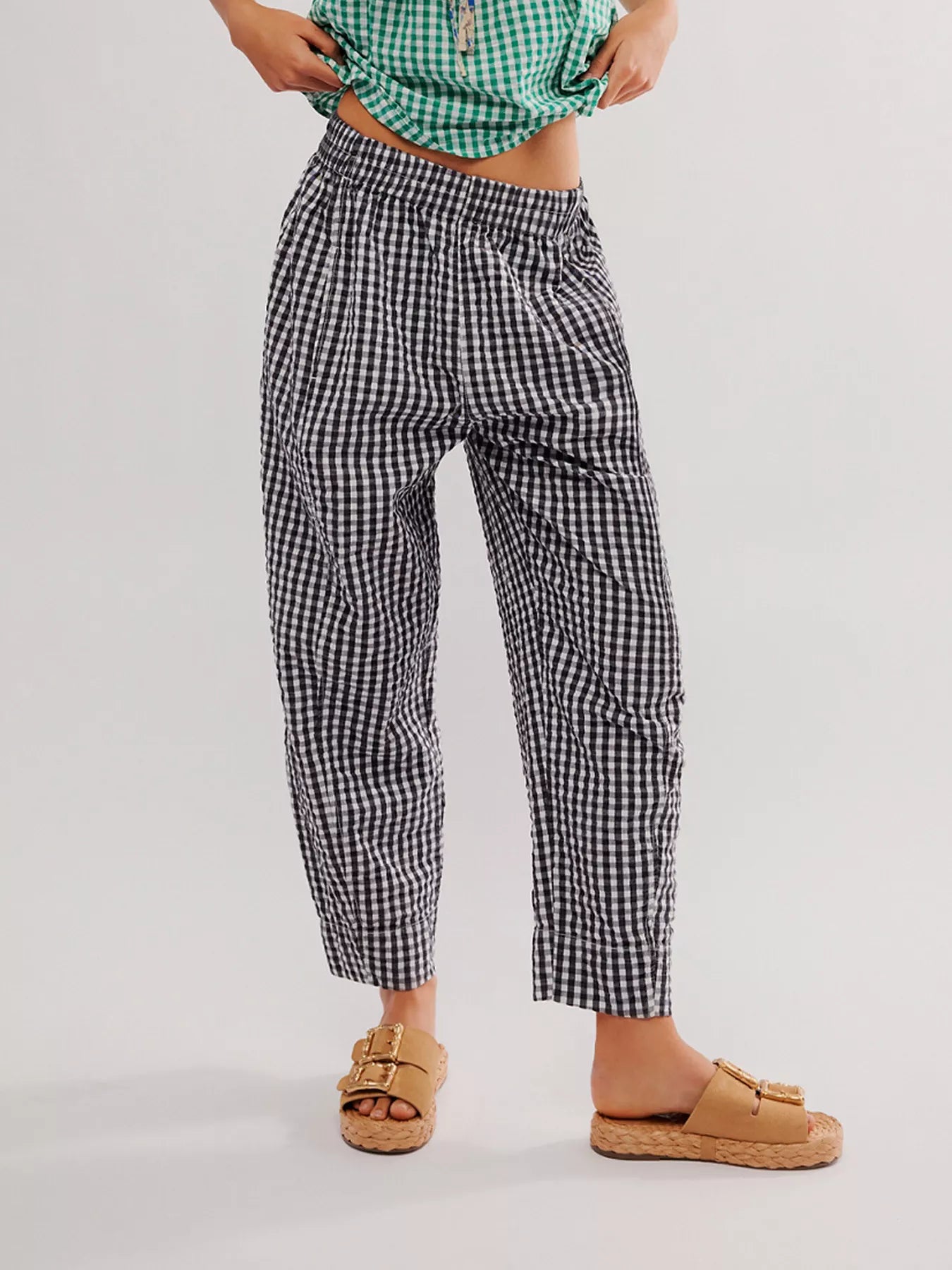 Person wearing black and white checkered pants on a plain background