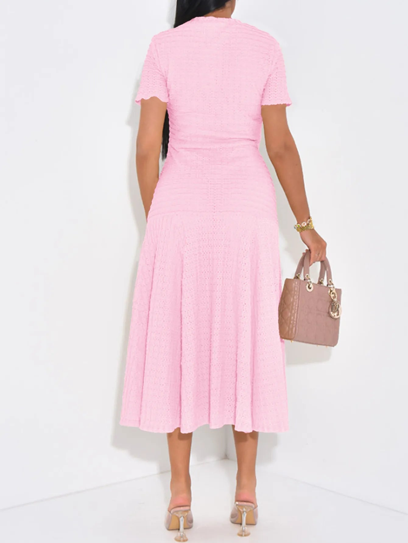 Person wearing a pink dress holding a matching handbag on a white background