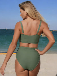 Woman wearing a green bikini set on a beach with ocean in the background