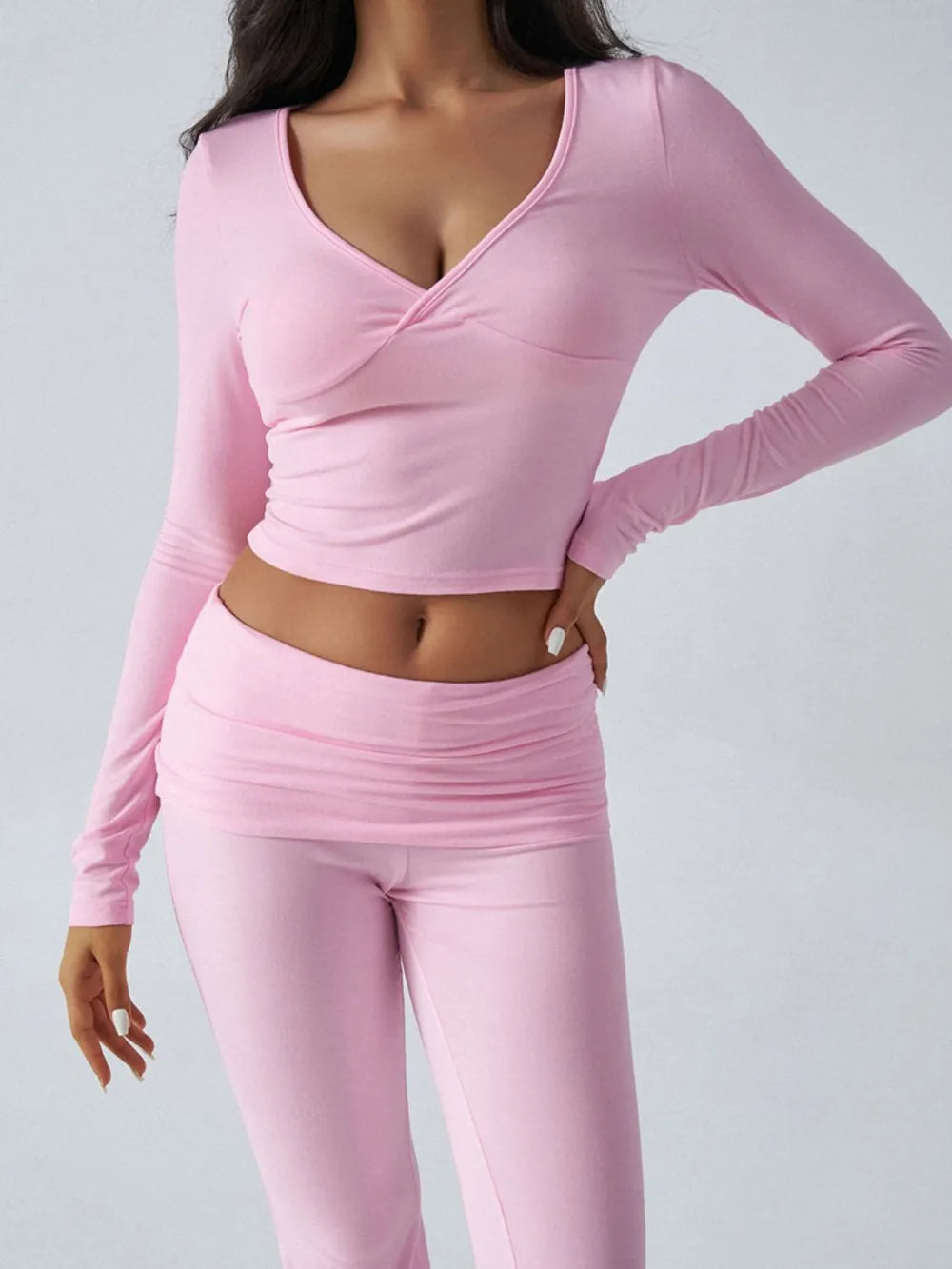 Person wearing a pink long-sleeve top and pants on a gray background