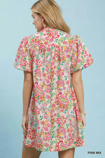 Woman wearing a colorful floral dress against a light blue background