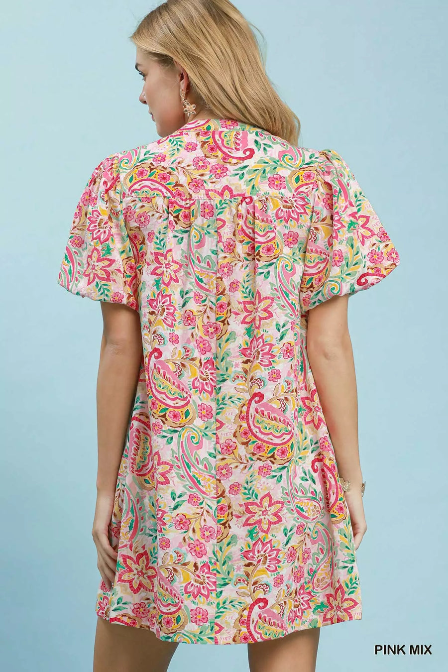 Woman wearing a colorful floral dress against a light blue background