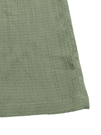 Close-up of a textured green fabric corner on a white background