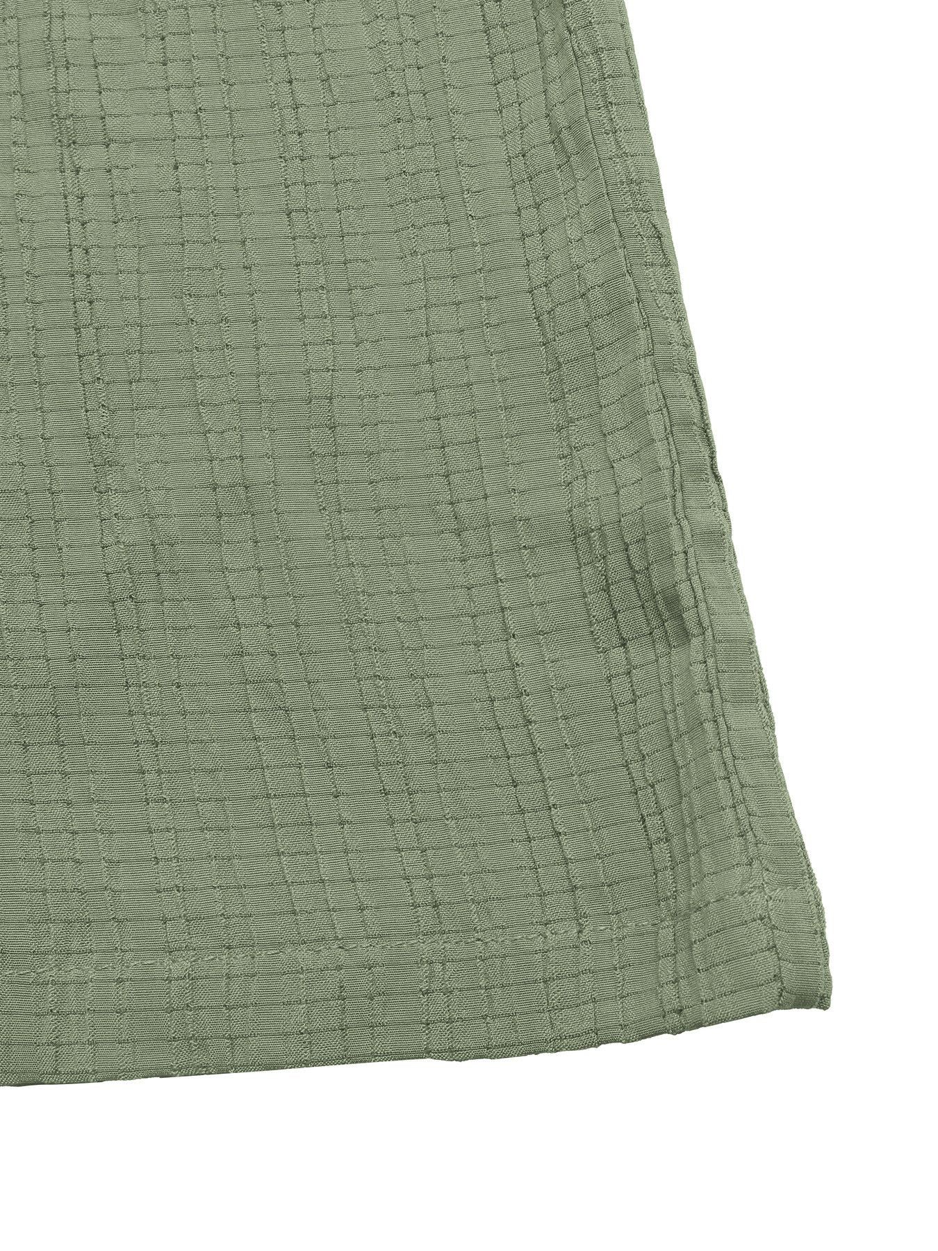 Close-up of a textured green fabric corner on a white background