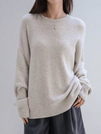 Person wearing a beige sweater against a plain background