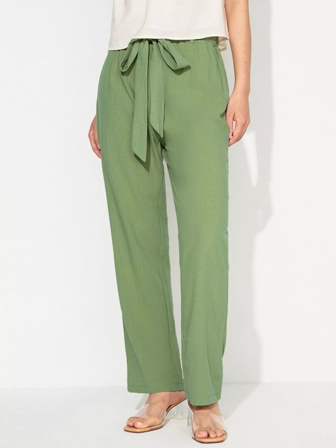 Green pants with a tie waist worn by a person on a white background