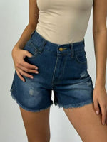 Person wearing blue denim shorts and a beige top on a plain background