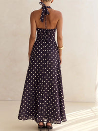 Woman wearing a long polka dot dress with a plain background