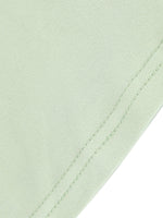 Close-up of a light green fabric with a visible seam on a white background