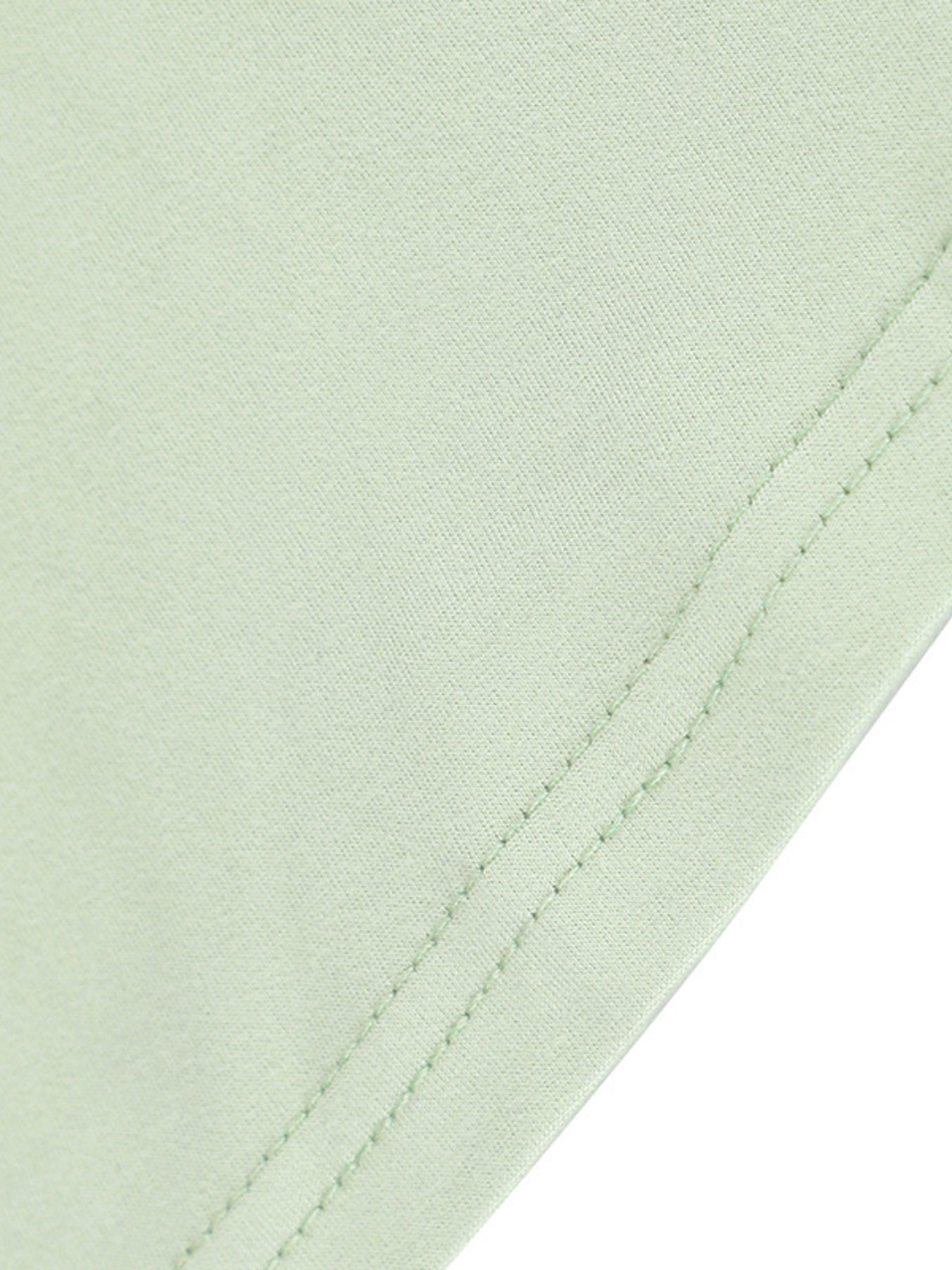 Close-up of a light green fabric with a visible seam on a white background