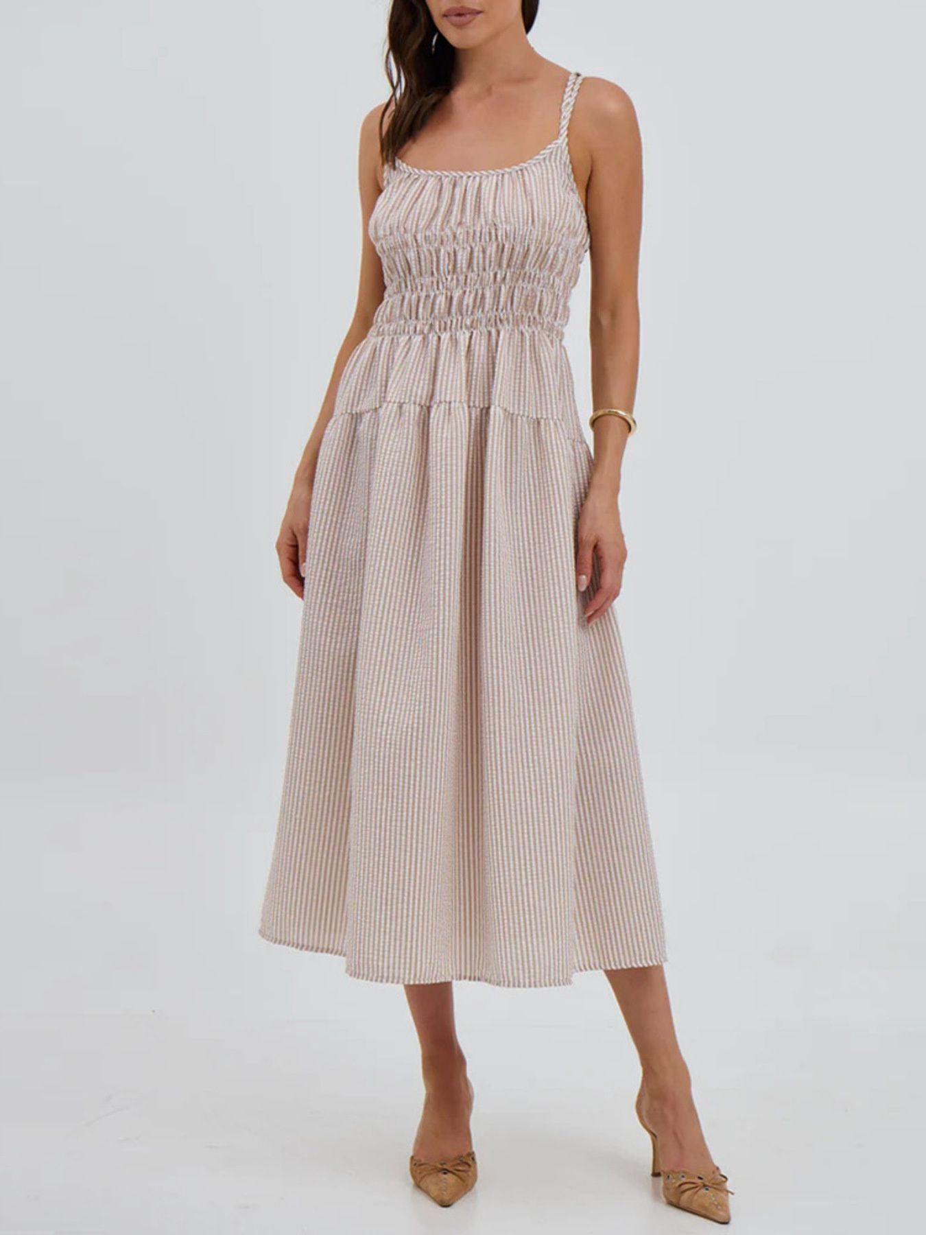 Woman wearing a beige and white striped dress on a white background