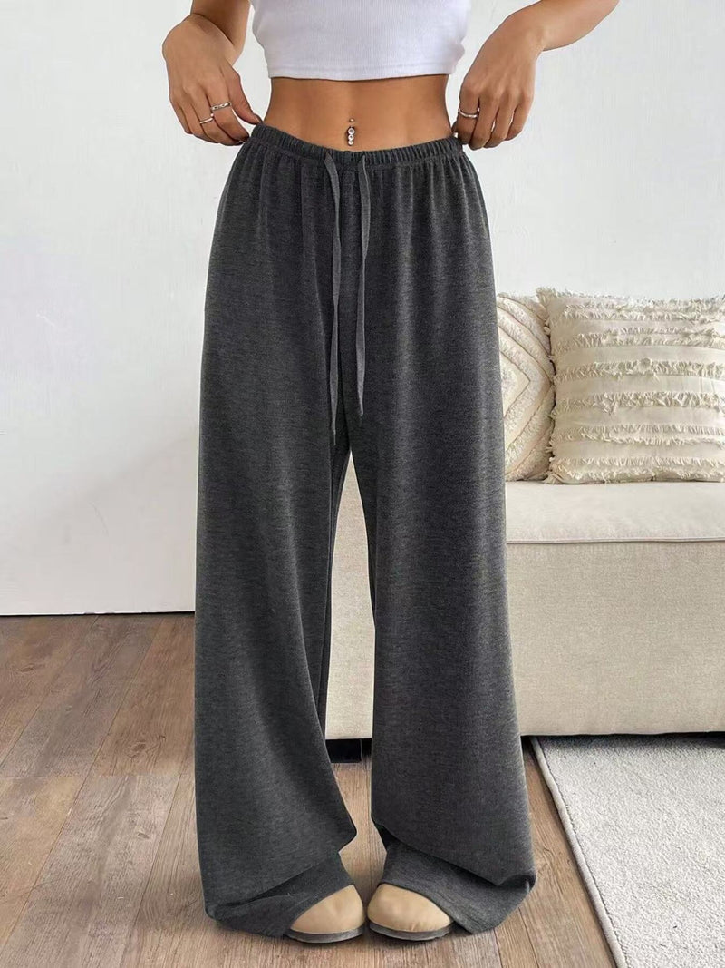 Person wearing dark gray wide-leg pants in a living room setting.