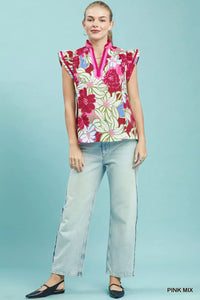 Woman wearing a colorful floral sleeveless top and light blue jeans on a light blue background