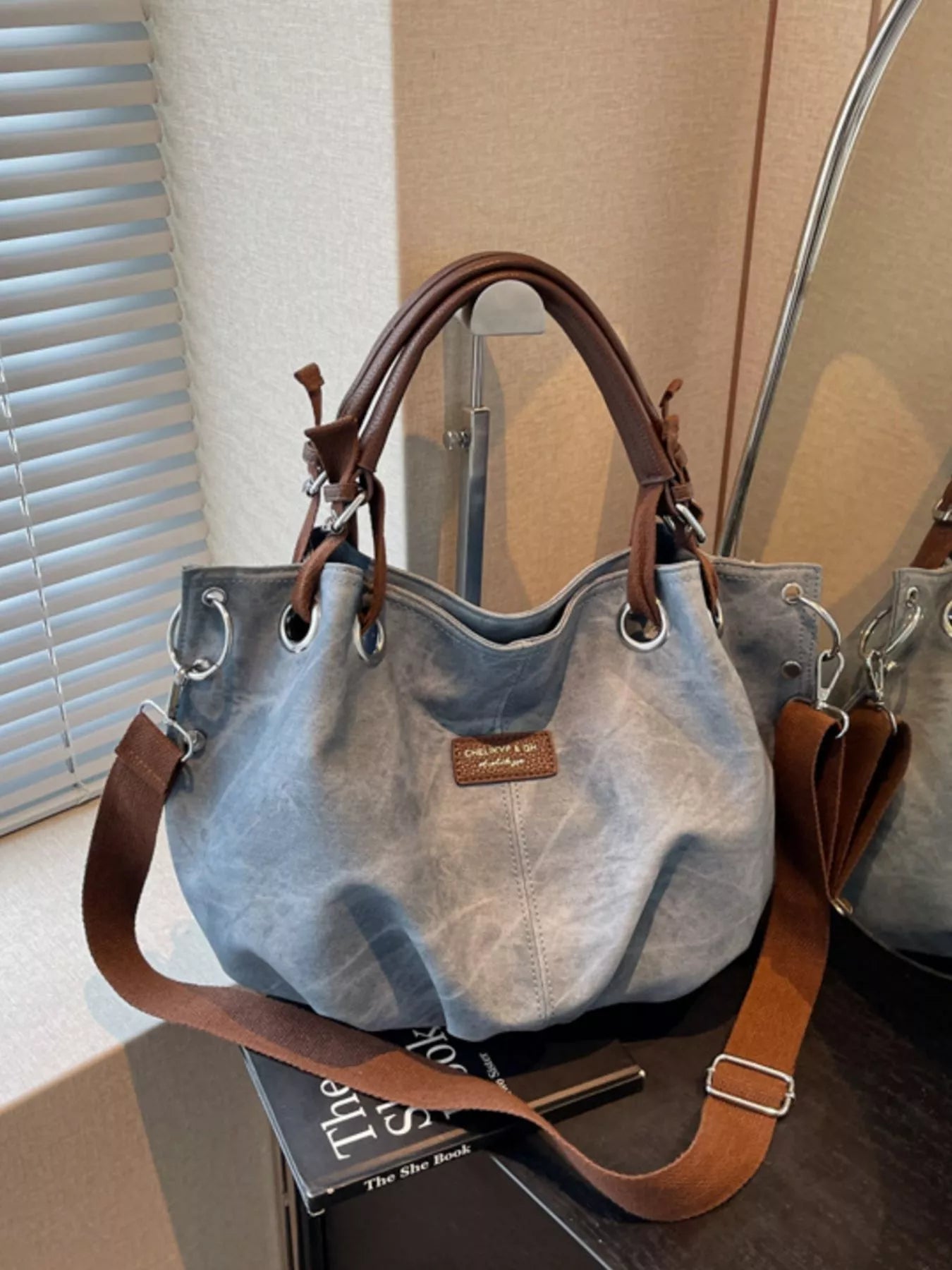 Gray handbag with brown straps on a surface