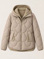 A beige quilted puffer jacket with a hood, shown against a solid off-white background. The jacket features a unique wavy quilting pattern and ribbed trim.