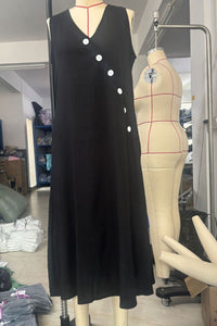 Black sleeveless dress with white buttons on a mannequin in a store setting.