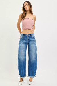 Woman wearing a pink strapless top and blue jeans on a white background