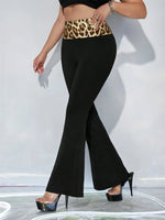 Person wearing black flared pants with a leopard print waistband on a white background