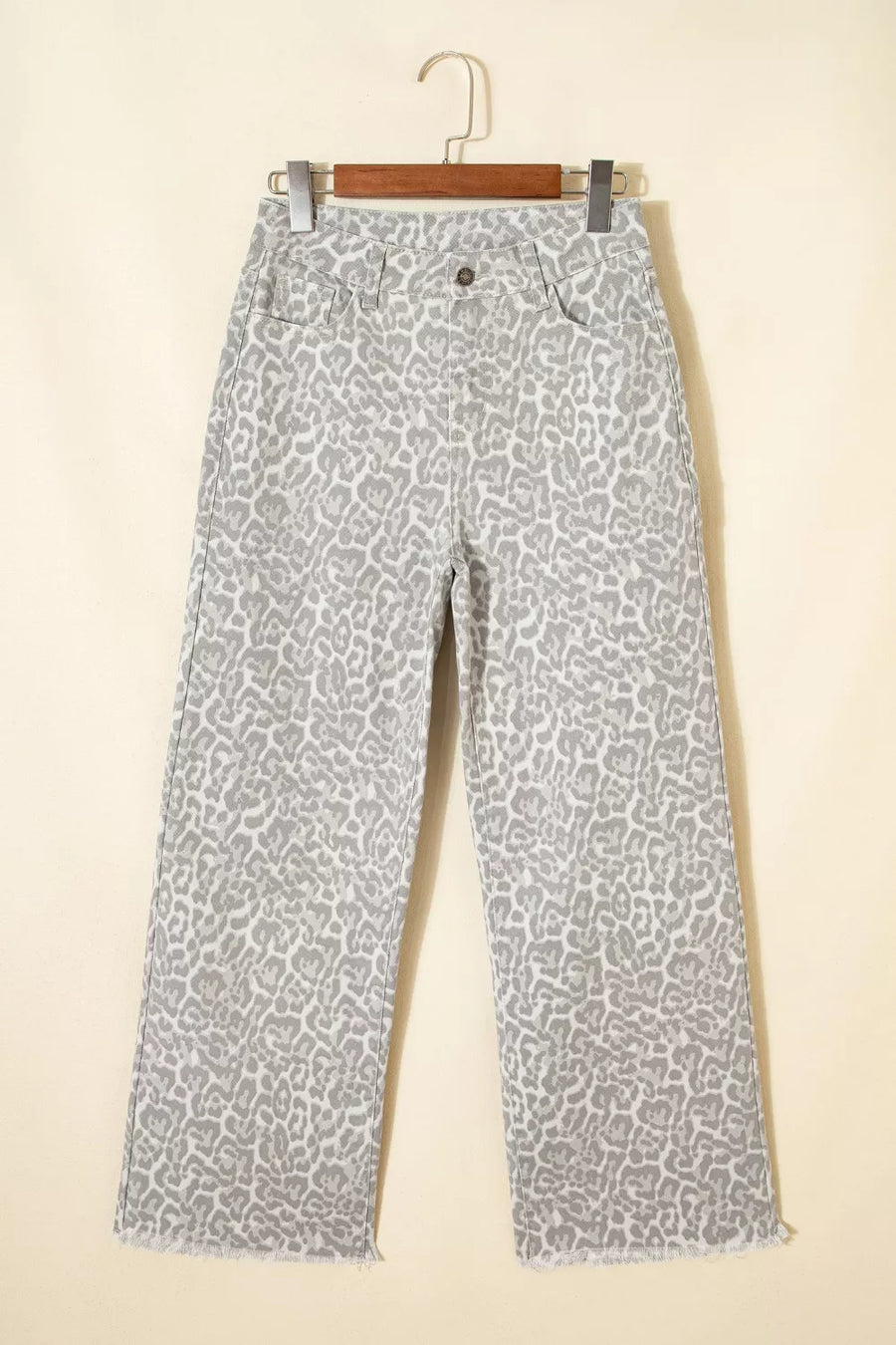 Leopard print pants on a hanger against a beige background