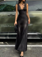 Woman in a black satin dress standing next to a green car