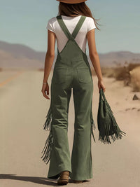 Person wearing green fringed overalls and a white top in a desert setting