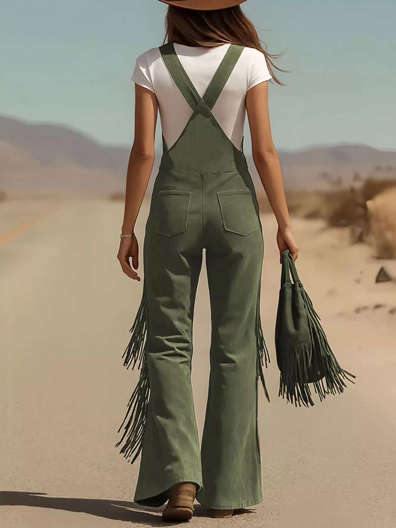 Person wearing green fringed overalls and a white top in a desert setting