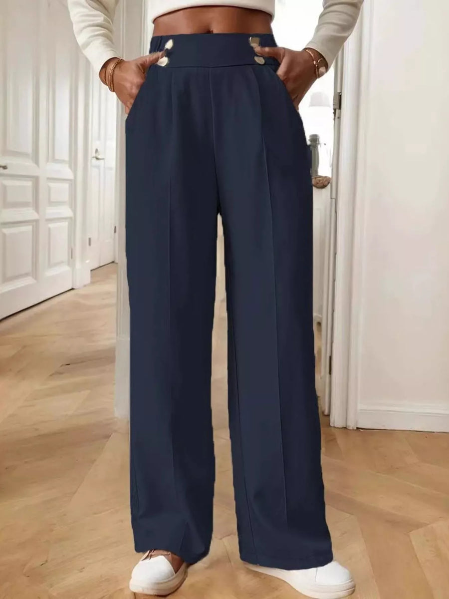 Person wearing navy wide-leg pants with a white top in a room with wooden flooring.