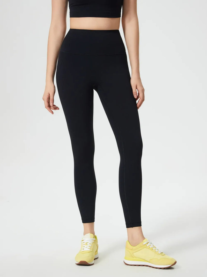 Person wearing black leggings and yellow sneakers on a white background