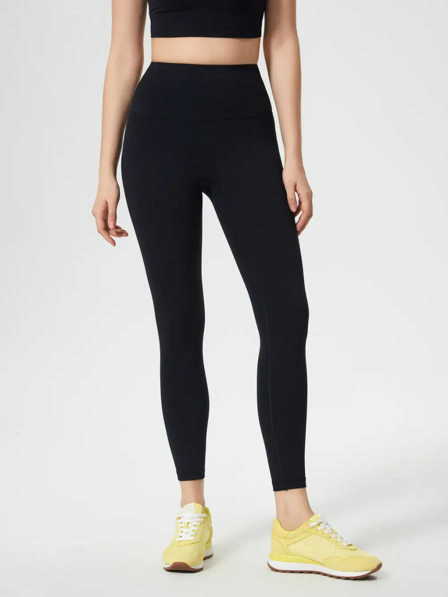 Person wearing black leggings and yellow sneakers on a white background