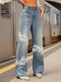 Person wearing blue jeans with lace details on a subway platform