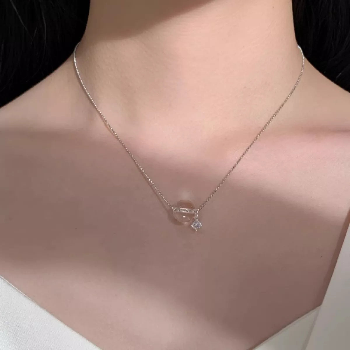 Necklace with a pendant on a person's neck against a neutral background