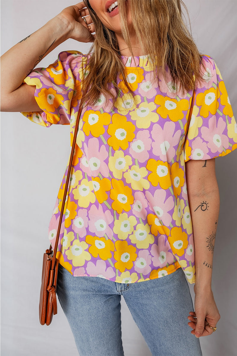 Woman wearing a colorful floral blouse with a plain background