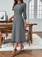 Woman wearing a black and white checkered dress in a dining room setting