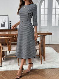 Woman wearing a black and white checkered dress in a dining room setting
