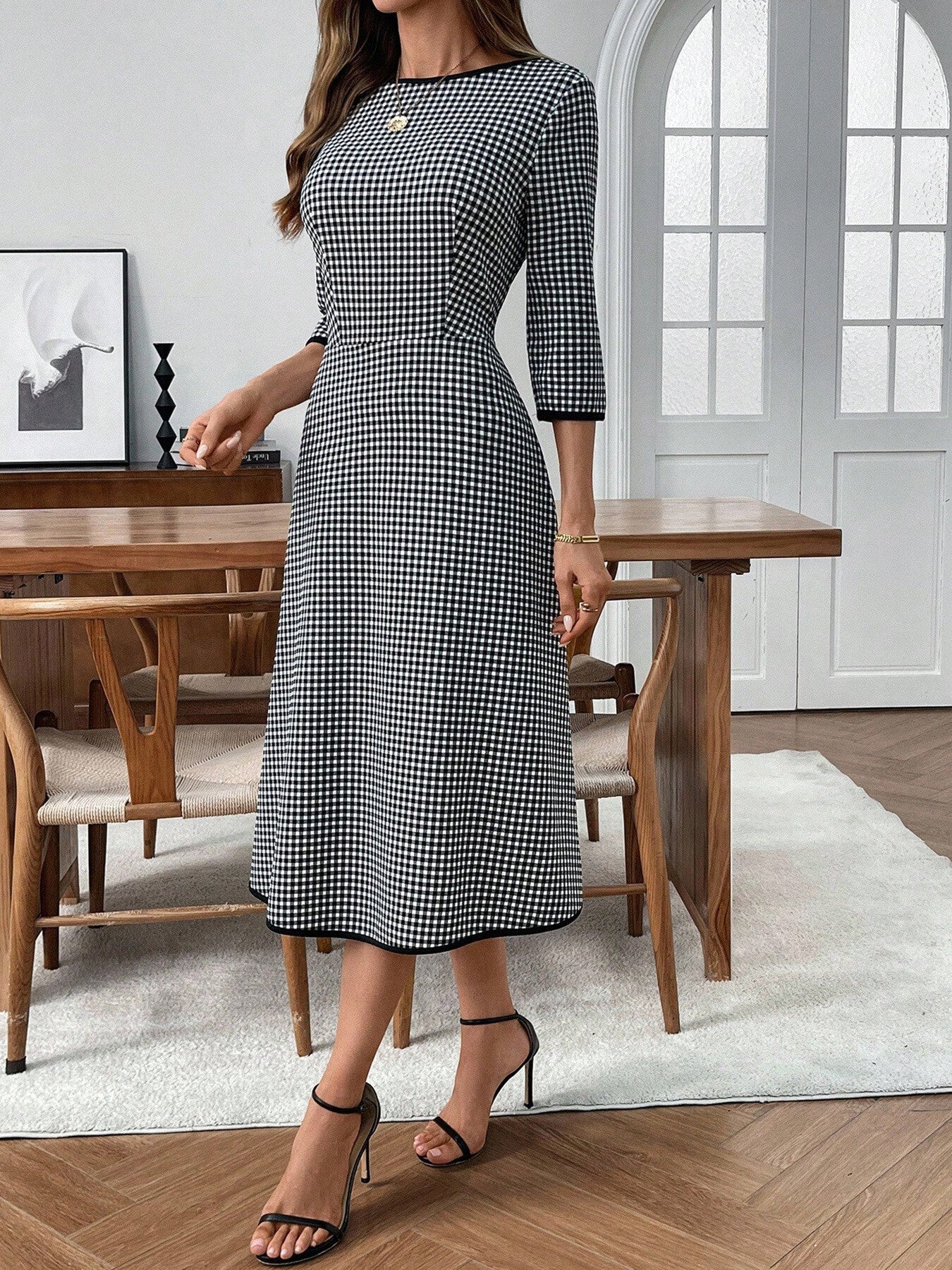 Woman wearing a black and white checkered dress in a dining room setting